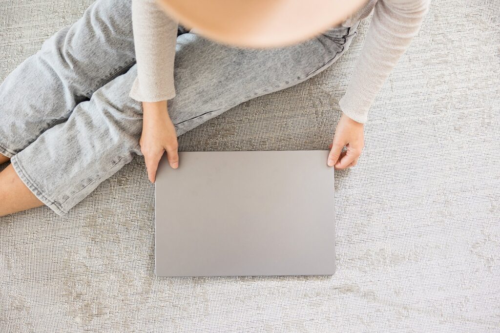 Woman sitting on rug opening a laptop to fix the SEO mistakes on her website.