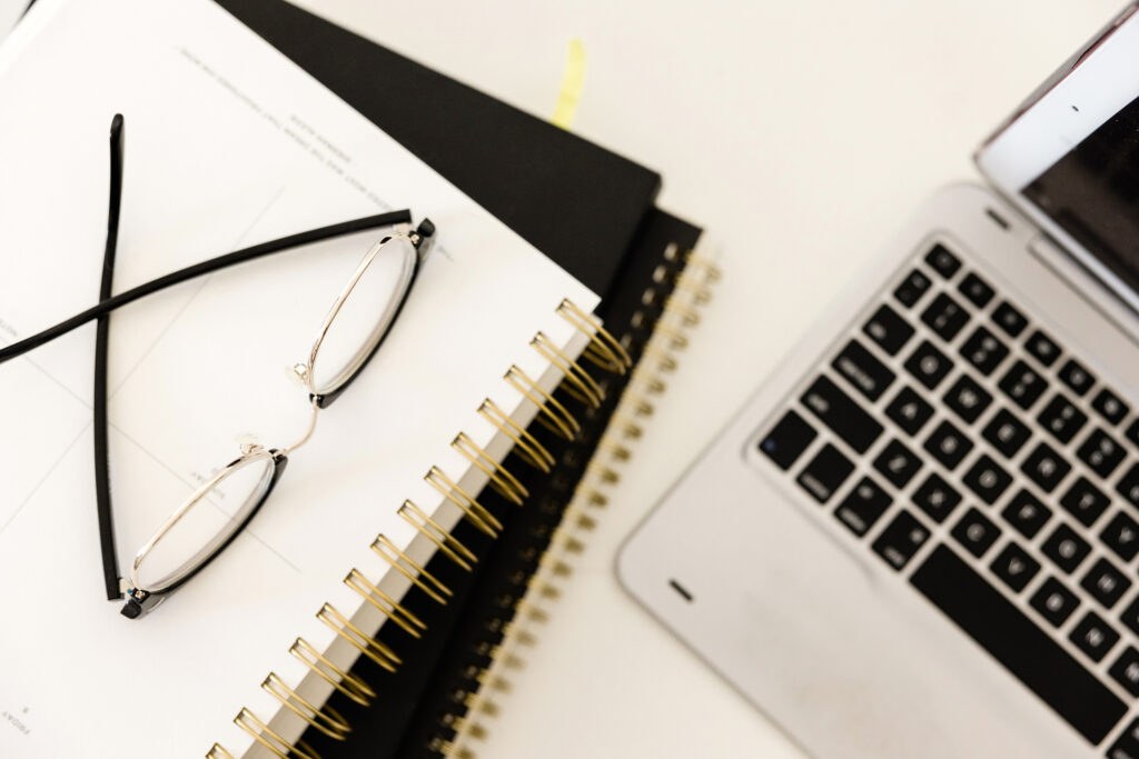 a computer with a notebook and glasses
