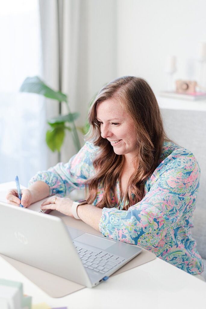 a headshot of melissa arlena sitting at her desk taking notes from her photography business coach