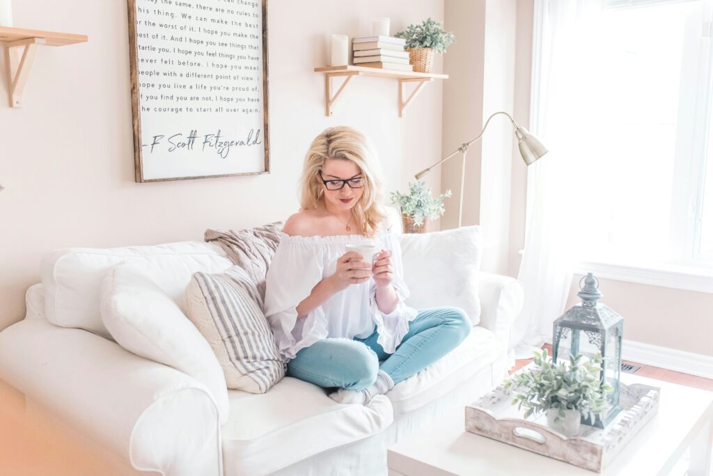 a woman sits and drinks coffee while sitting on her couch