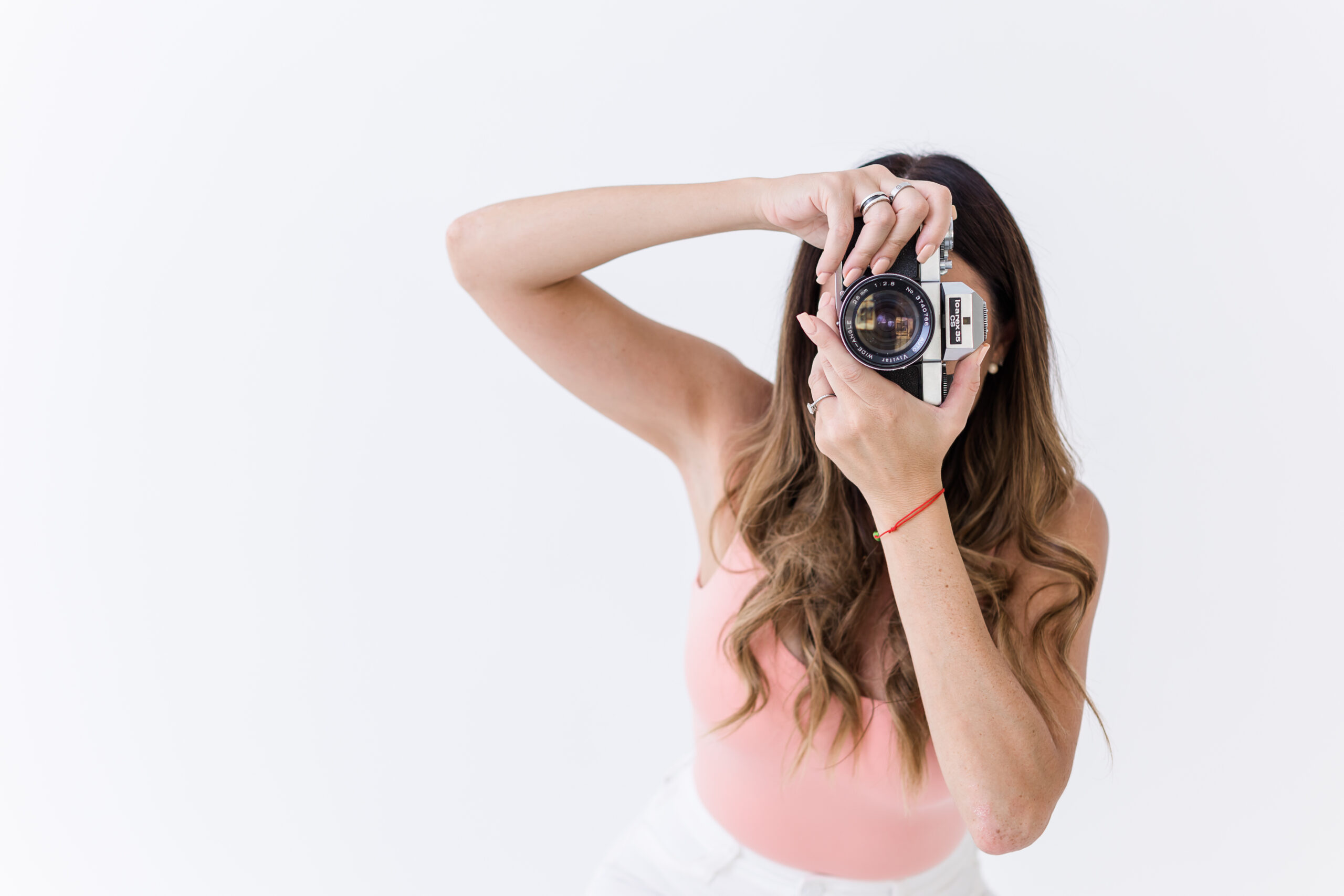 photographer points camera at viewer while thinking about ways to get photography clients